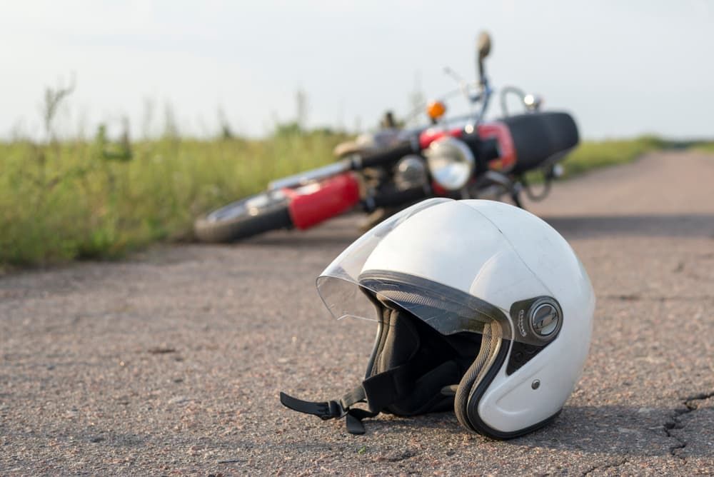 Motorcycle helmet lies on road beside bike, symbolizing importance of Florida’s helmet laws in accidents.