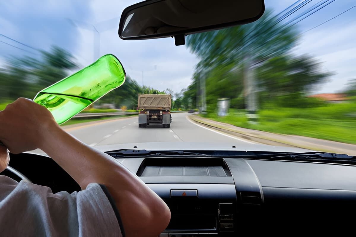 Woman drinking while driving a truck.
