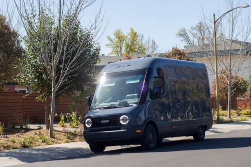 Dark blue Amazon delivery van driving through a residential neighborhood on a sunny day