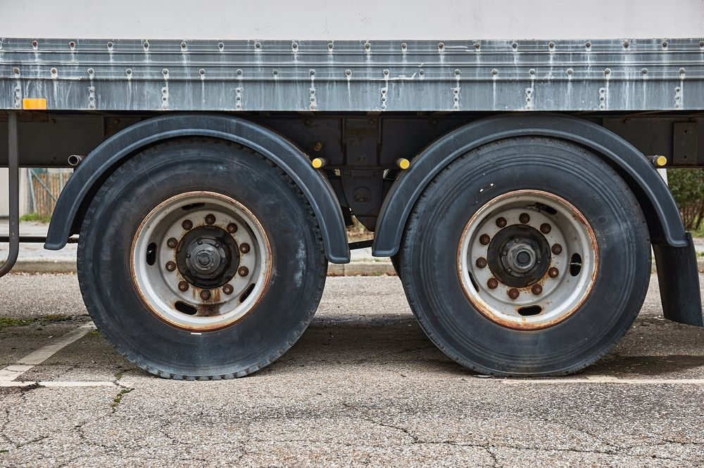 Two large dual rear tires on a semi-trailer, viewed from the side, with a blue checkmark in the upper right corner