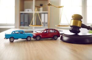 two toy cars and a scale representing car accident litigation