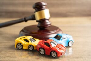 A judge's gavel beside toy cars, symbolizing a vehicle accident insurance claim or court case.