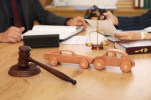 Wooden cars with judge's gavel on lawyer's table during meeting with insurance adjusters in office.