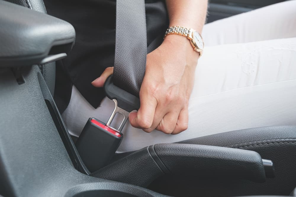 Woman driver fastens her seat belt before driving.