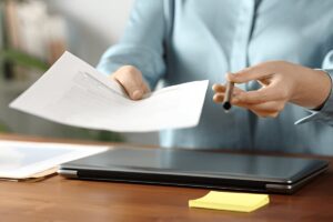 Close up portrait of a office worker giving you contract to sign and pen on a wooden table