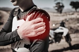 Injured biker holds shoulder in pain after accident or muscle strain.