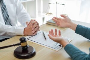 Lawyer consulting with a client at a desk with legal documents and gavel.