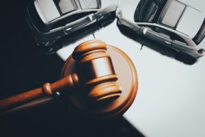 Close up of a wooden gavel with two toy cars beside it representing a car accident lawsuit.