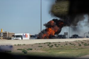 FedEx truck on highway near a fire with black smoke rising into the sky