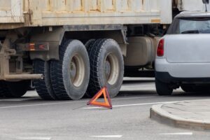 Close up of a stopped truck with a warning triangle placed on the road near the rear wheels.