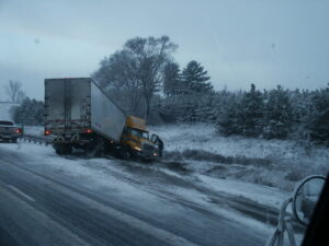 Jackknifed semi truck on a snowy highway shoulder after losing control