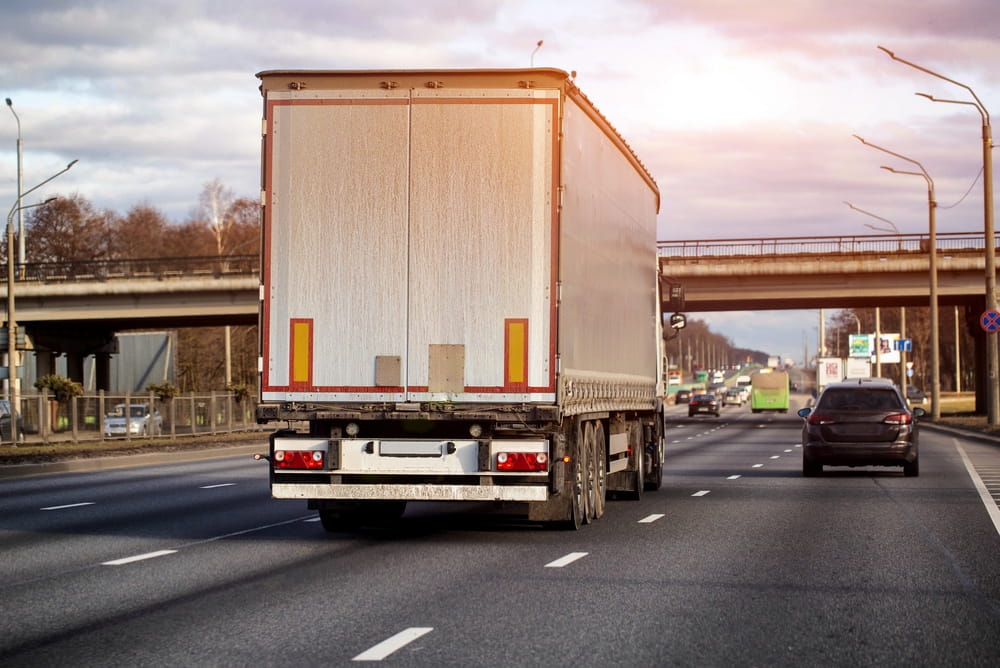 Rear view of a semi-trailer driving on a highway near a passenger car
